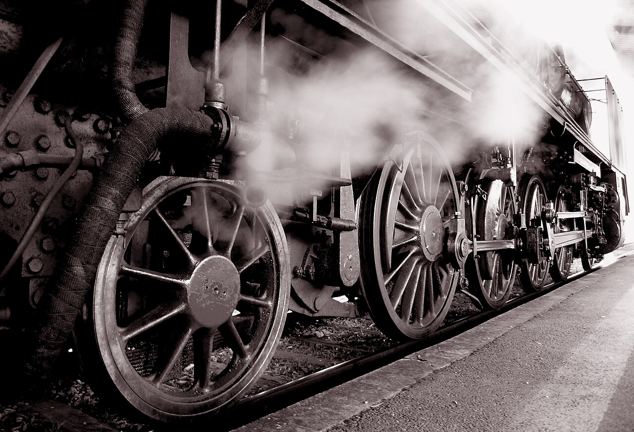 A shiny old steam train resting at a station.